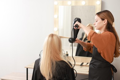 Photo of Hairdresser blow drying client's hair in salon