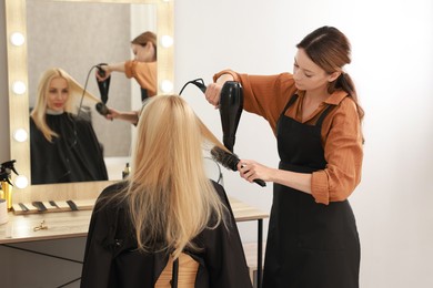 Photo of Hairdresser blow drying client's hair in salon