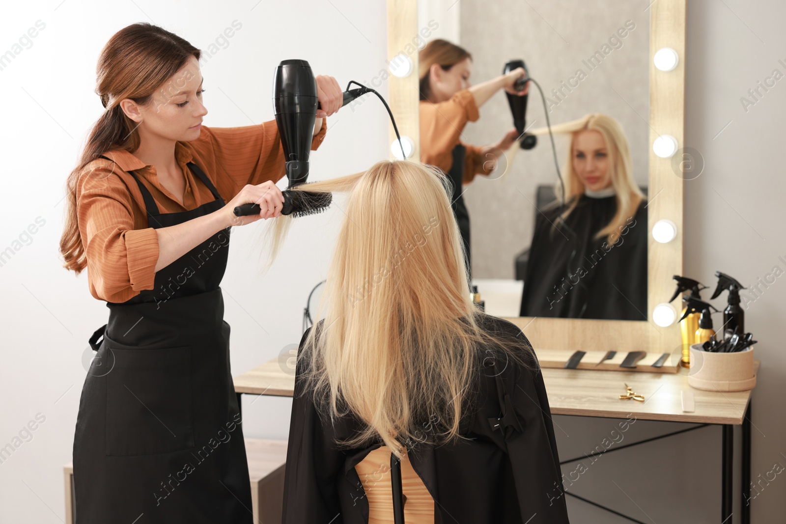 Photo of Hairdresser blow drying client's hair in salon