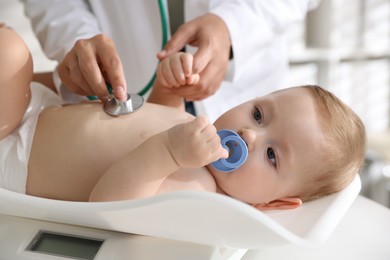 Photo of Pediatrician examining little child with stethoscope in clinic, closeup. Checking baby's health