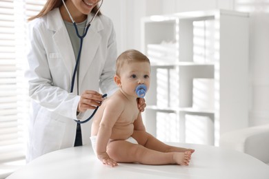 Photo of Pediatrician examining little child with stethoscope in clinic, closeup. Checking baby's health