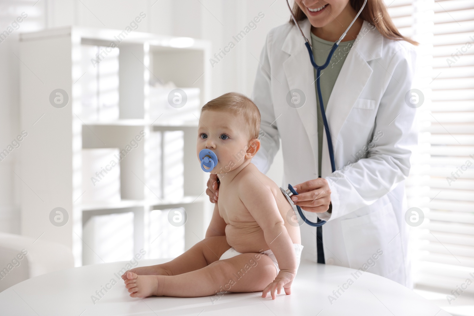 Photo of Pediatrician examining little child with stethoscope in clinic, closeup. Checking baby's health