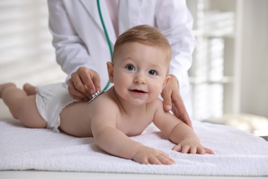 Photo of Pediatrician examining little child with stethoscope in clinic, closeup. Checking baby's health