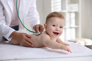 Photo of Pediatrician examining little child with stethoscope in clinic, closeup. Checking baby's health