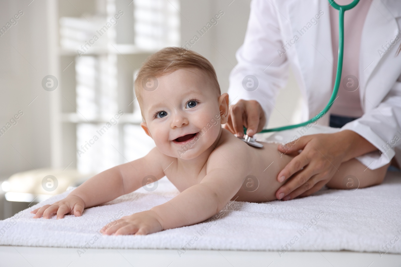 Photo of Pediatrician examining little child with stethoscope in clinic, closeup. Checking baby's health