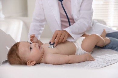 Photo of Pediatrician examining little child with stethoscope in clinic, closeup. Checking baby's health