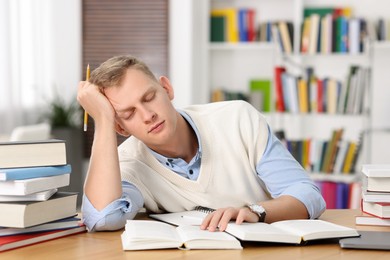 Photo of Preparing for exam. Tired student sleeping among books at table indoors