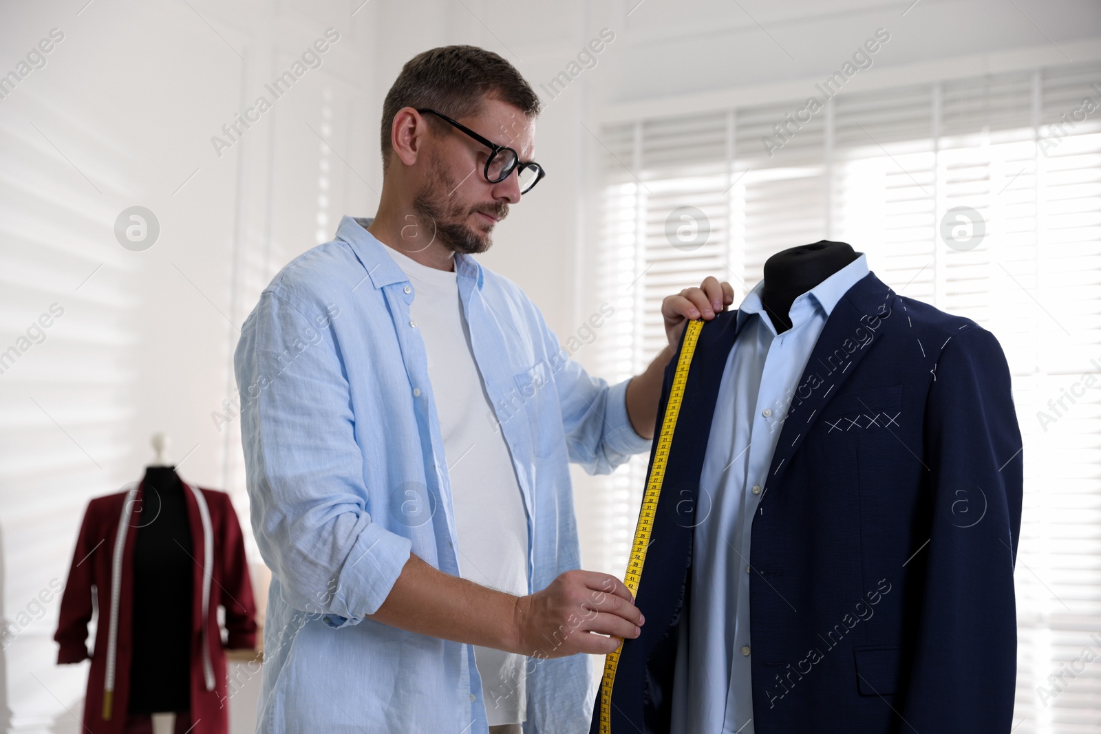 Photo of Man measuring black jacket with tape in atelier