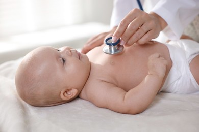 Photo of Pediatrician examining little child with stethoscope in clinic, closeup. Checking baby's health