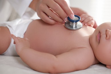 Photo of Pediatrician examining little child with stethoscope in clinic, closeup. Checking baby's health