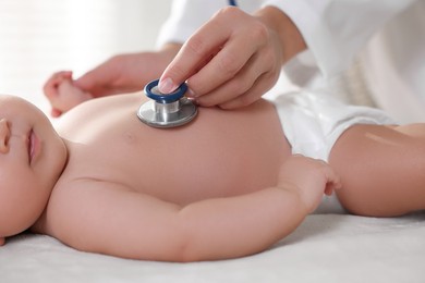 Photo of Pediatrician examining little child with stethoscope in clinic, closeup. Checking baby's health