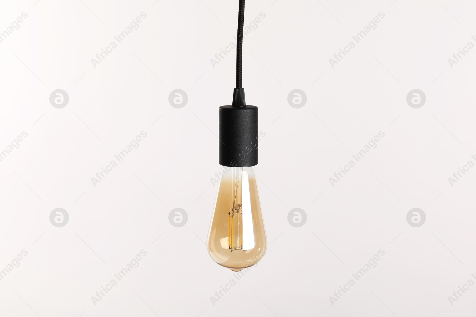 Photo of One light bulb hanging on cord against white background