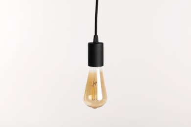 Photo of One light bulb hanging on cord against white background