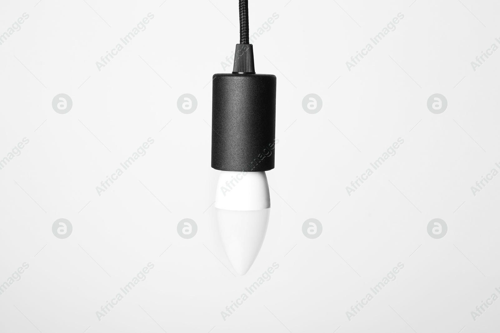 Photo of One light bulb hanging on cord against white background