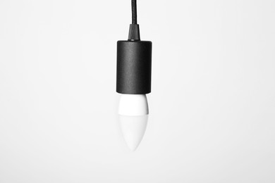 Photo of One light bulb hanging on cord against white background