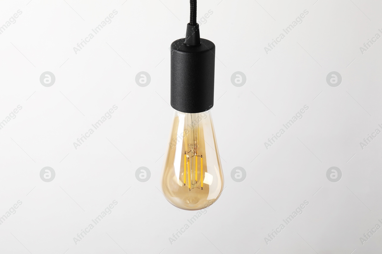 Photo of One light bulb hanging on cord against white background