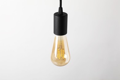 Photo of One light bulb hanging on cord against white background