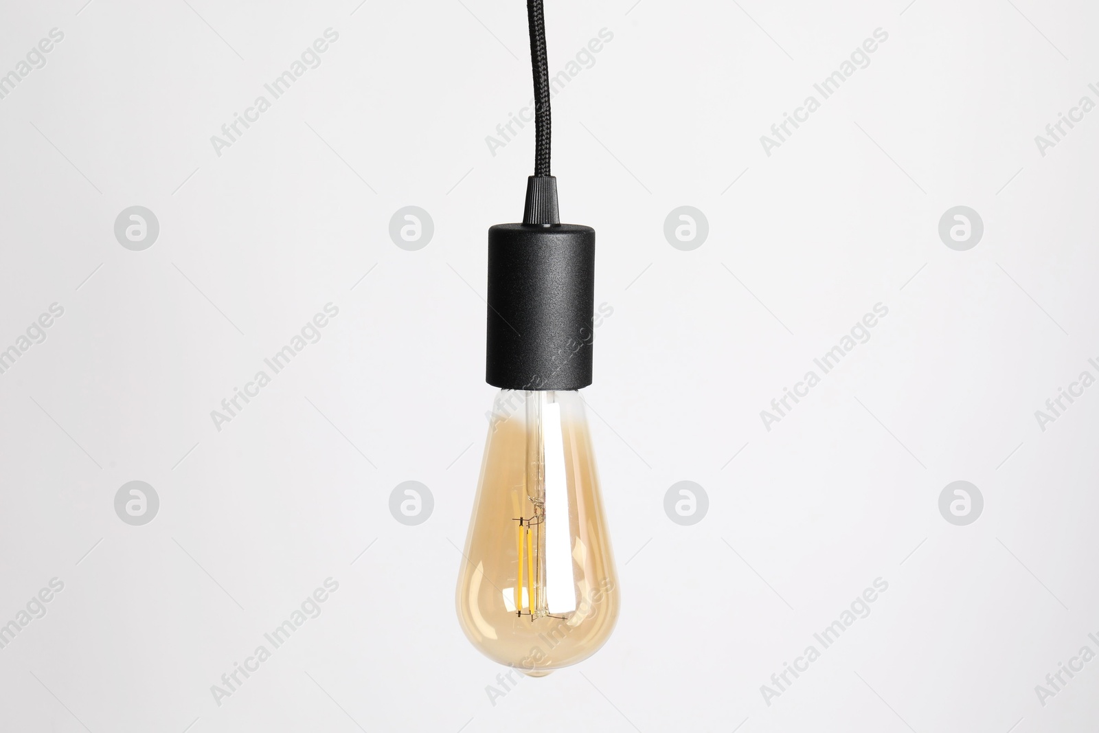 Photo of One light bulb hanging on cord against white background