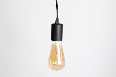 Photo of One light bulb hanging on cord against white background