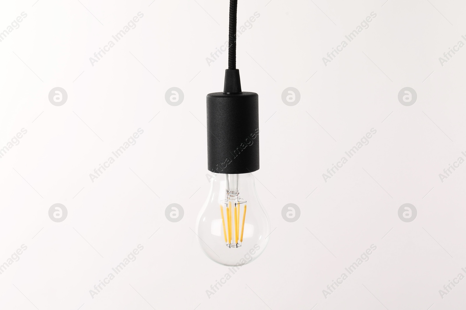 Photo of One light bulb hanging on cord against white background