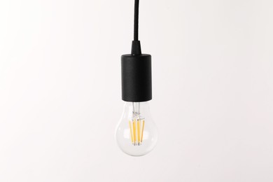 Photo of One light bulb hanging on cord against white background