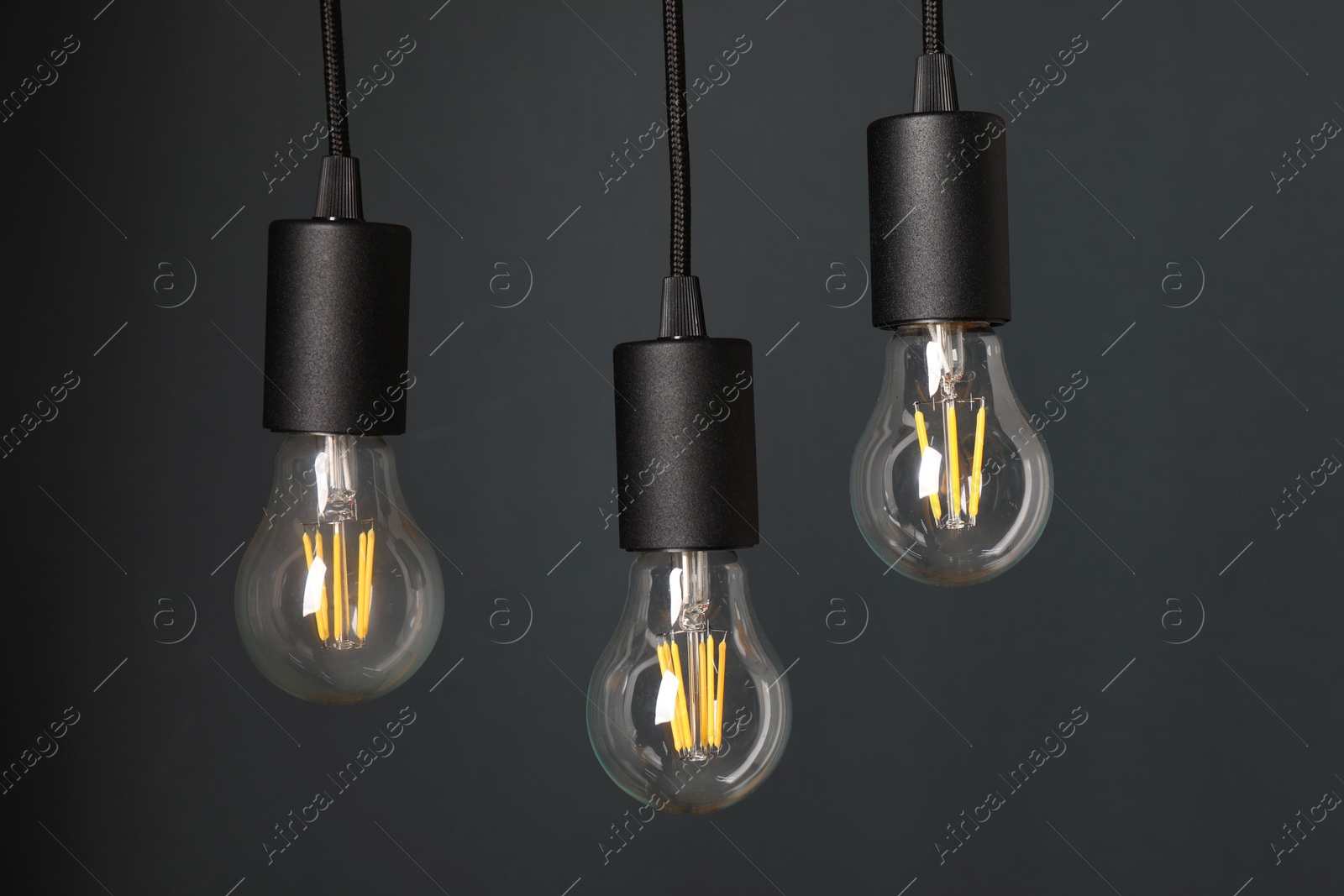 Photo of Light bulbs hanging on cords against grey background