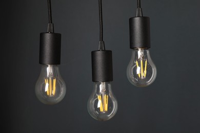 Photo of Light bulbs hanging on cords against grey background