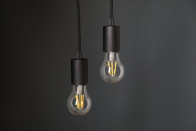 Photo of Light bulbs hanging on cords against grey background