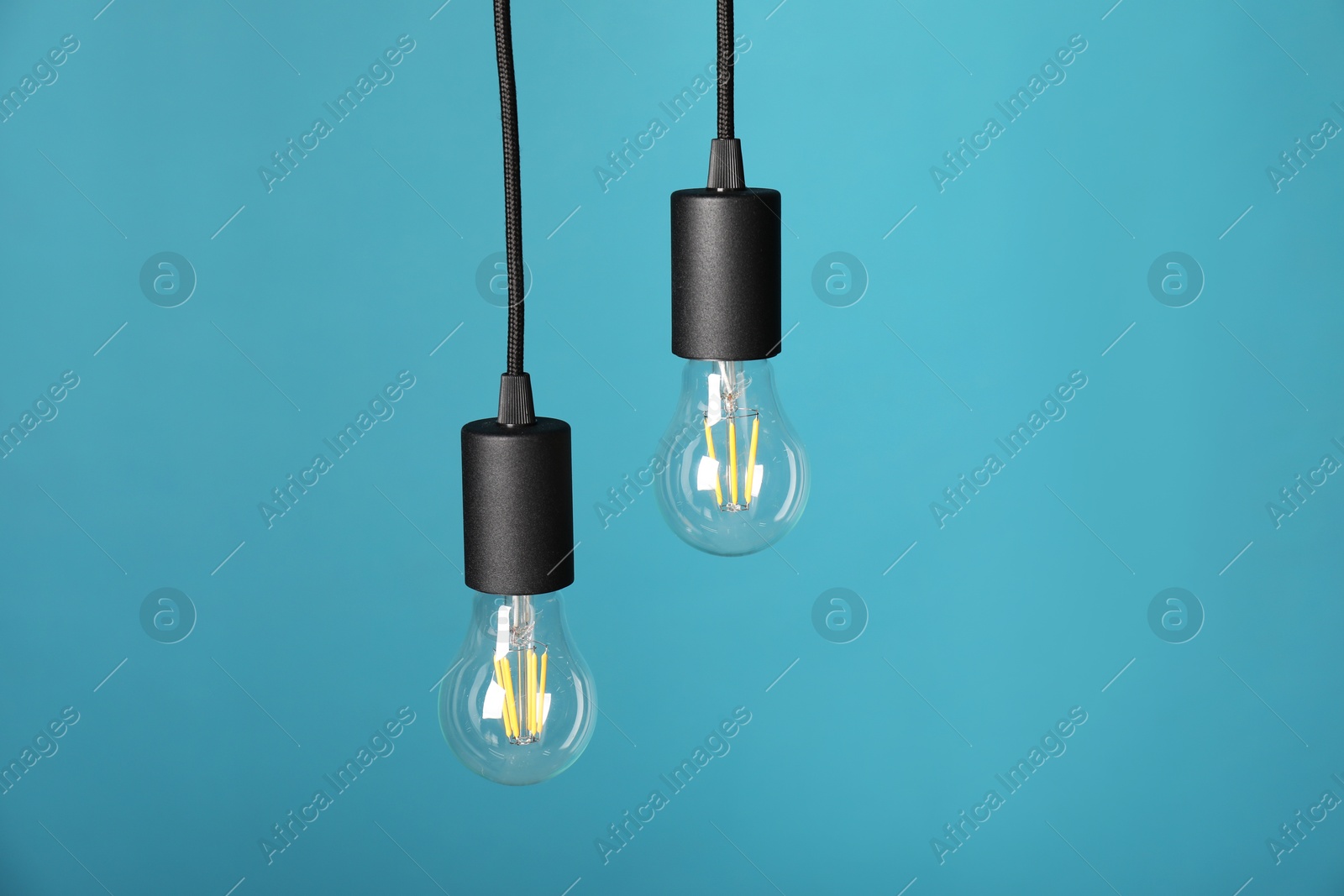 Photo of Light bulbs hanging on cords against light blue background