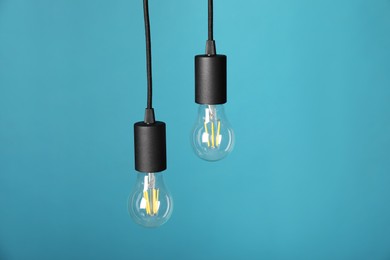 Photo of Light bulbs hanging on cords against light blue background