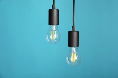 Photo of Light bulbs hanging on cords against light blue background