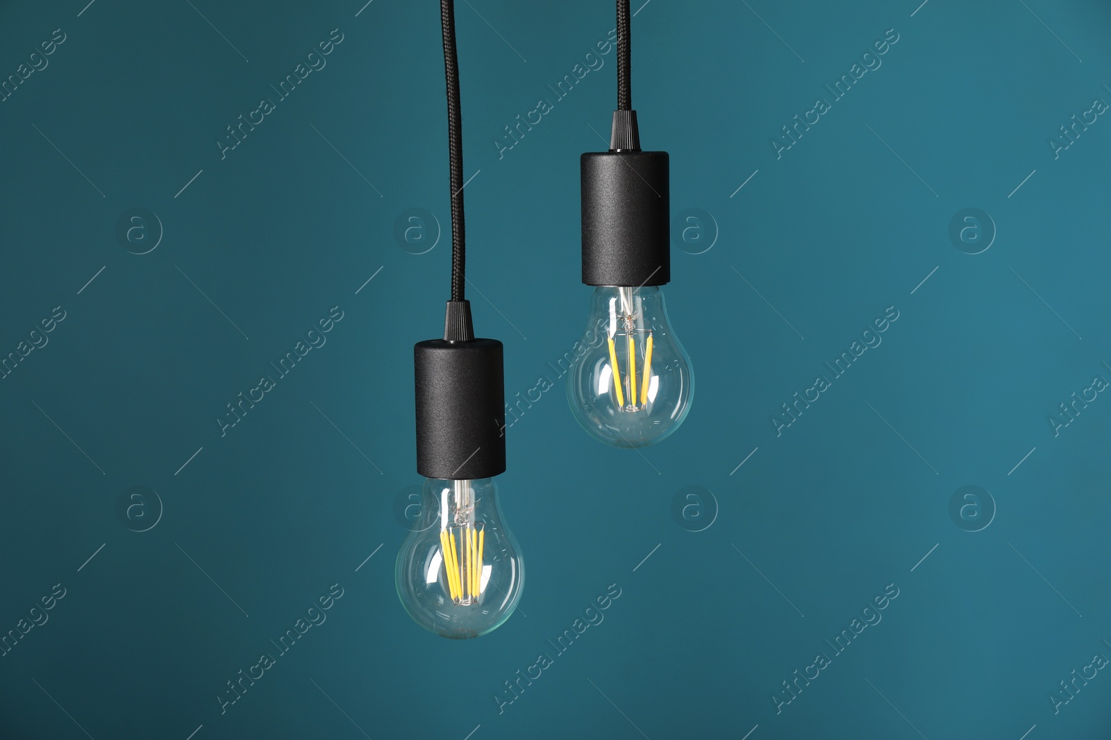 Photo of Light bulbs hanging on cords against light blue background