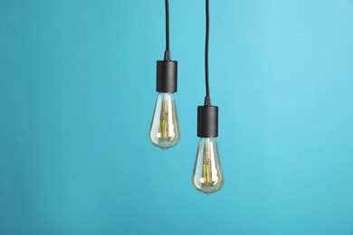 Photo of Light bulbs hanging on cords against light blue background