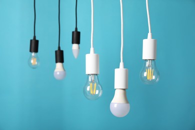 Photo of Light bulbs hanging on cords against light blue background