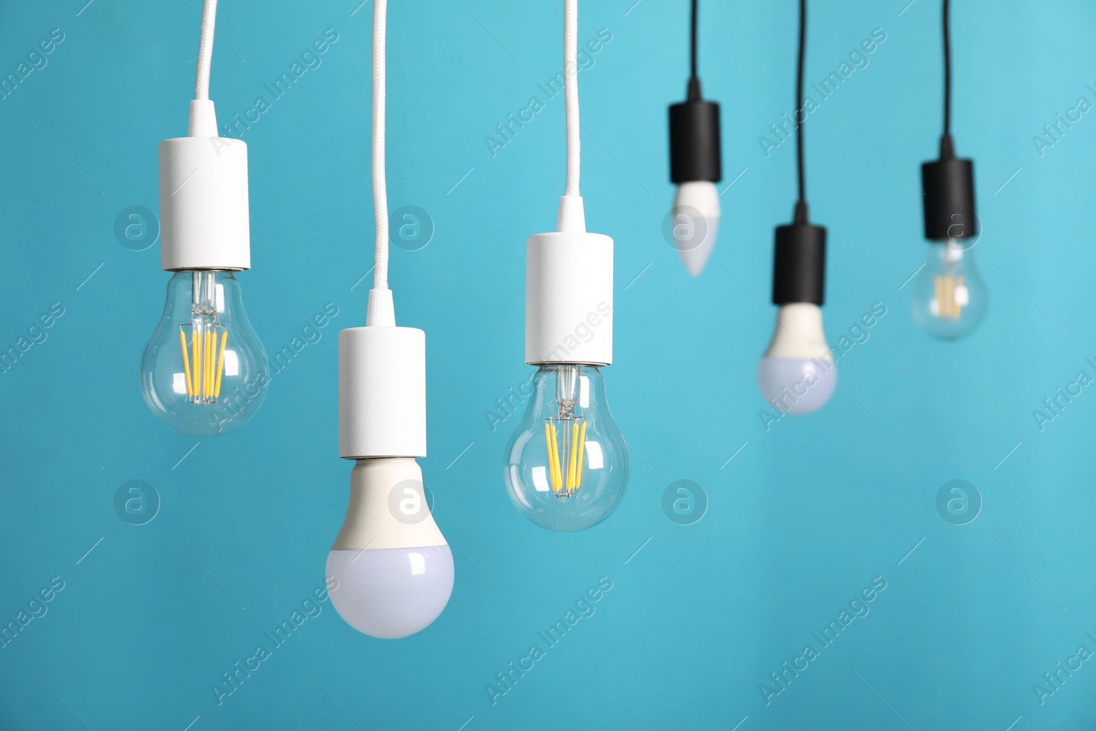 Photo of Light bulbs hanging on cords against light blue background