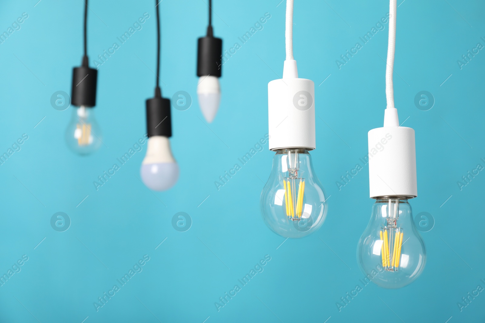 Photo of Light bulbs hanging on cords against light blue background