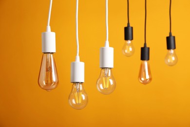 Photo of Light bulbs hanging on cords against orange background