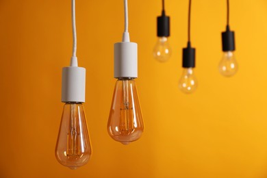 Photo of Light bulbs hanging on cords against orange background