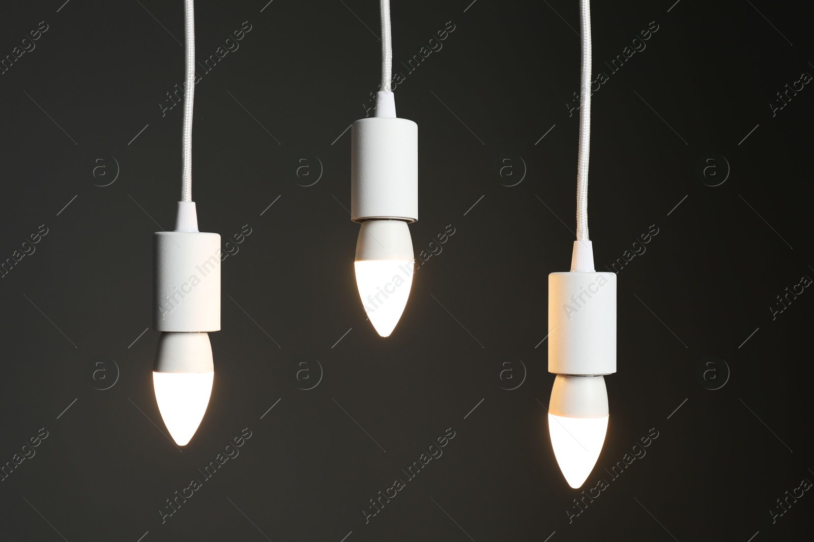 Photo of Light bulbs hanging on cords against grey background