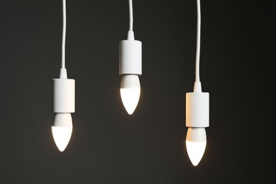 Photo of Light bulbs hanging on cords against grey background