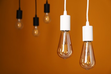 Photo of Light bulbs hanging on cords against orange background