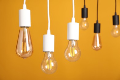 Photo of Light bulbs hanging on cords against orange background