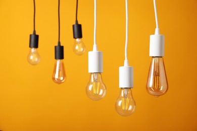 Photo of Light bulbs hanging on cords against orange background