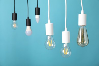 Photo of Light bulbs hanging on cords against light blue background