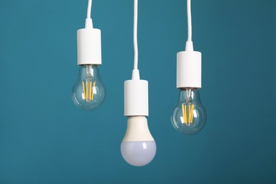 Photo of Light bulbs hanging on cords against light blue background