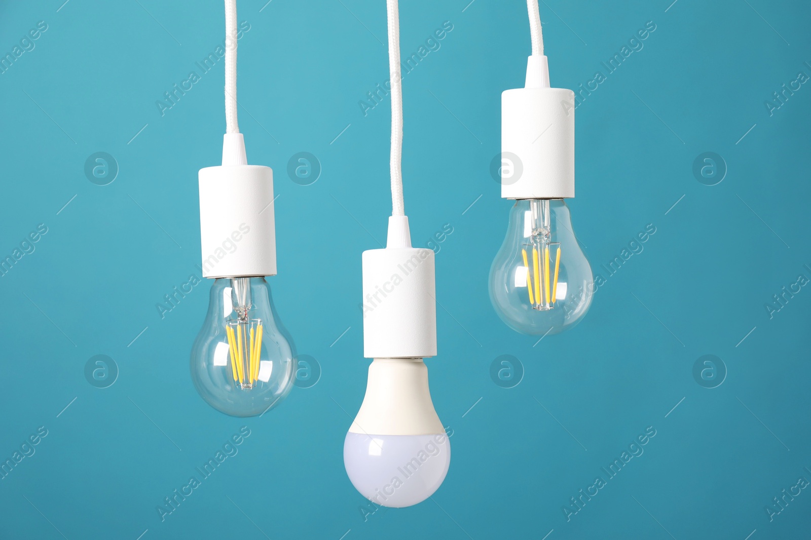 Photo of Light bulbs hanging on cords against light blue background