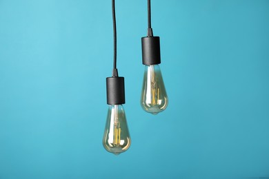 Photo of Light bulbs hanging on cords against light blue background