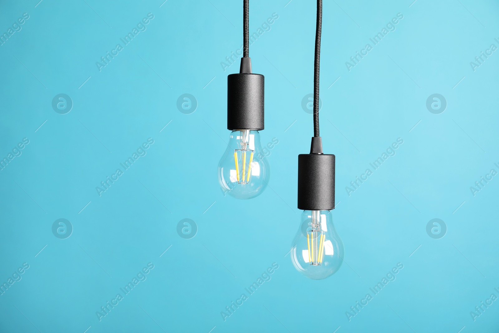 Photo of Light bulbs hanging on cords against light blue background