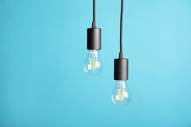 Photo of Light bulbs hanging on cords against light blue background