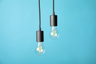 Photo of Light bulbs hanging on cords against light blue background